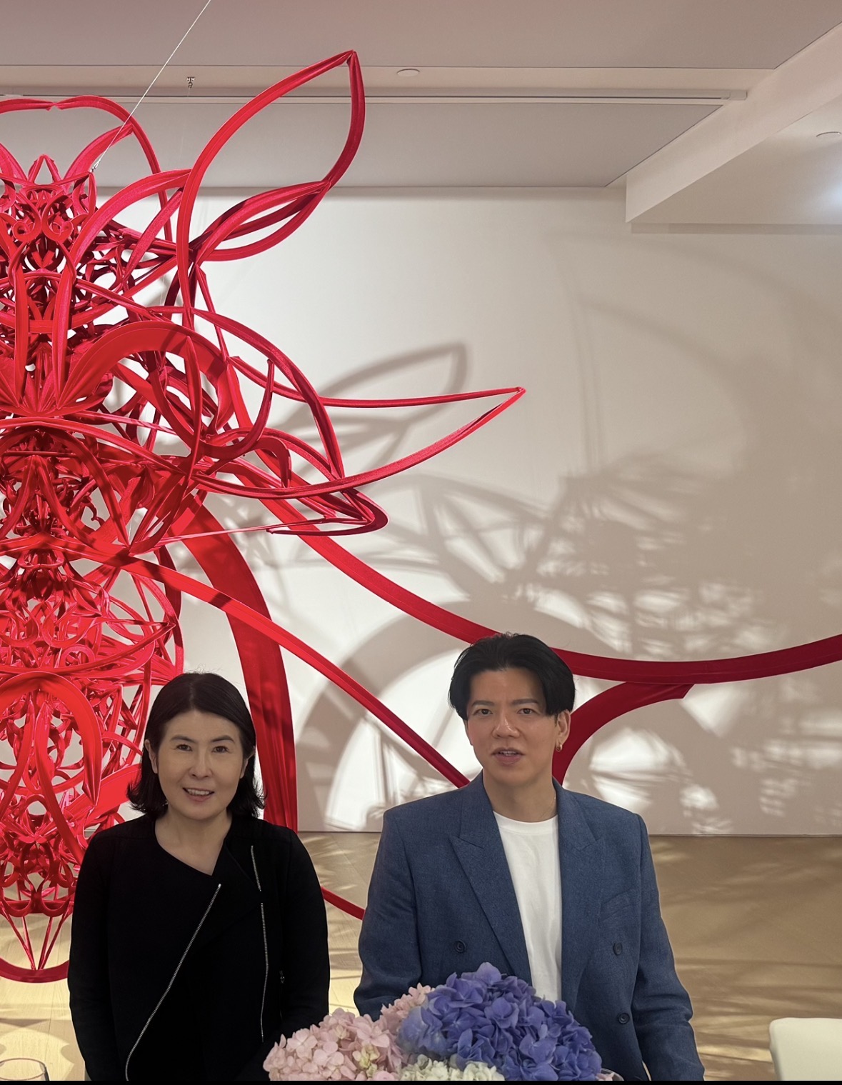 Kiyomi Soga and Hiroaki Ikeda in front of a work by Ryunosuke Okazaki