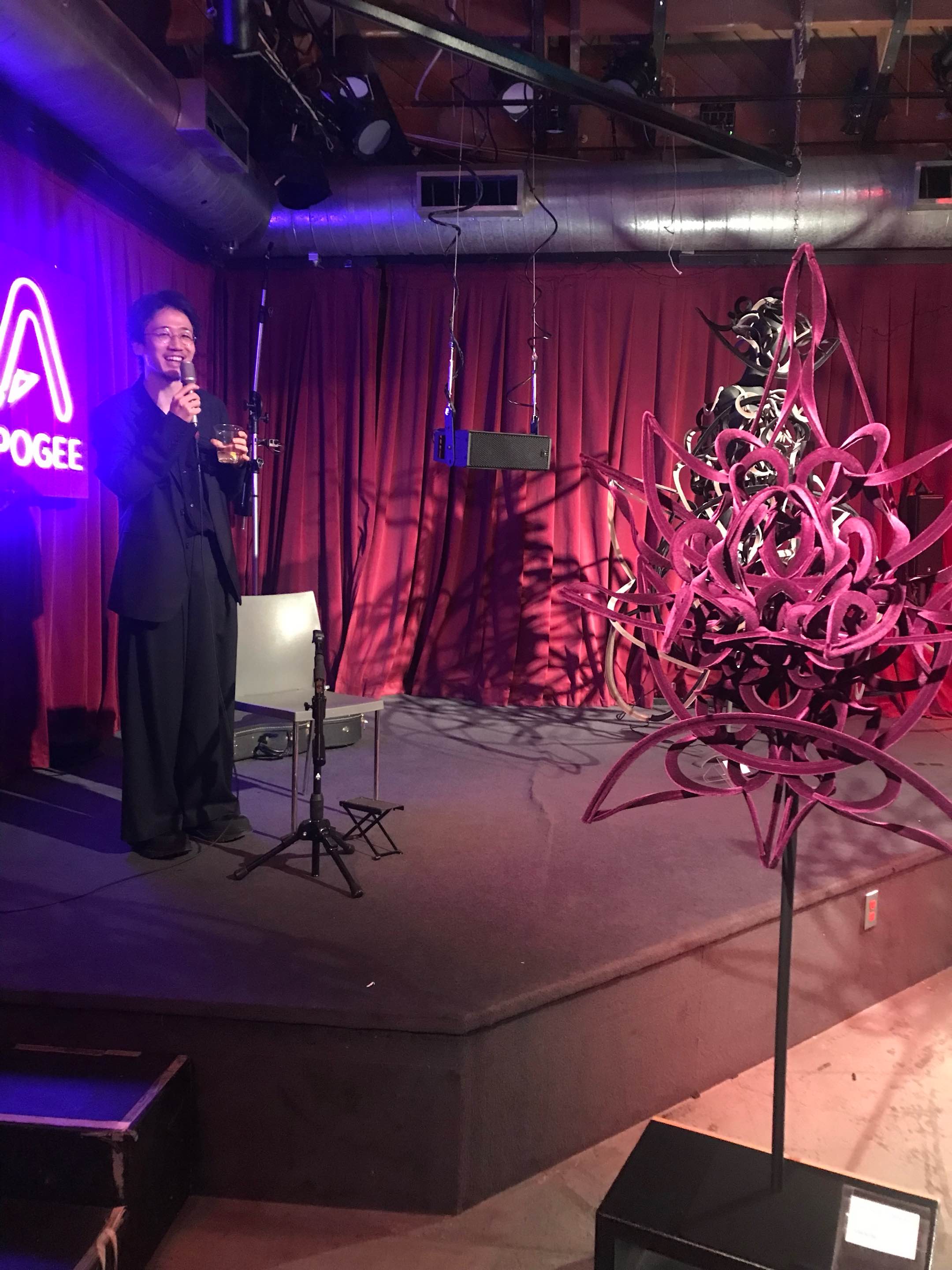 Ryunosuke Okazaki speaking beside his work at Apogee Studio